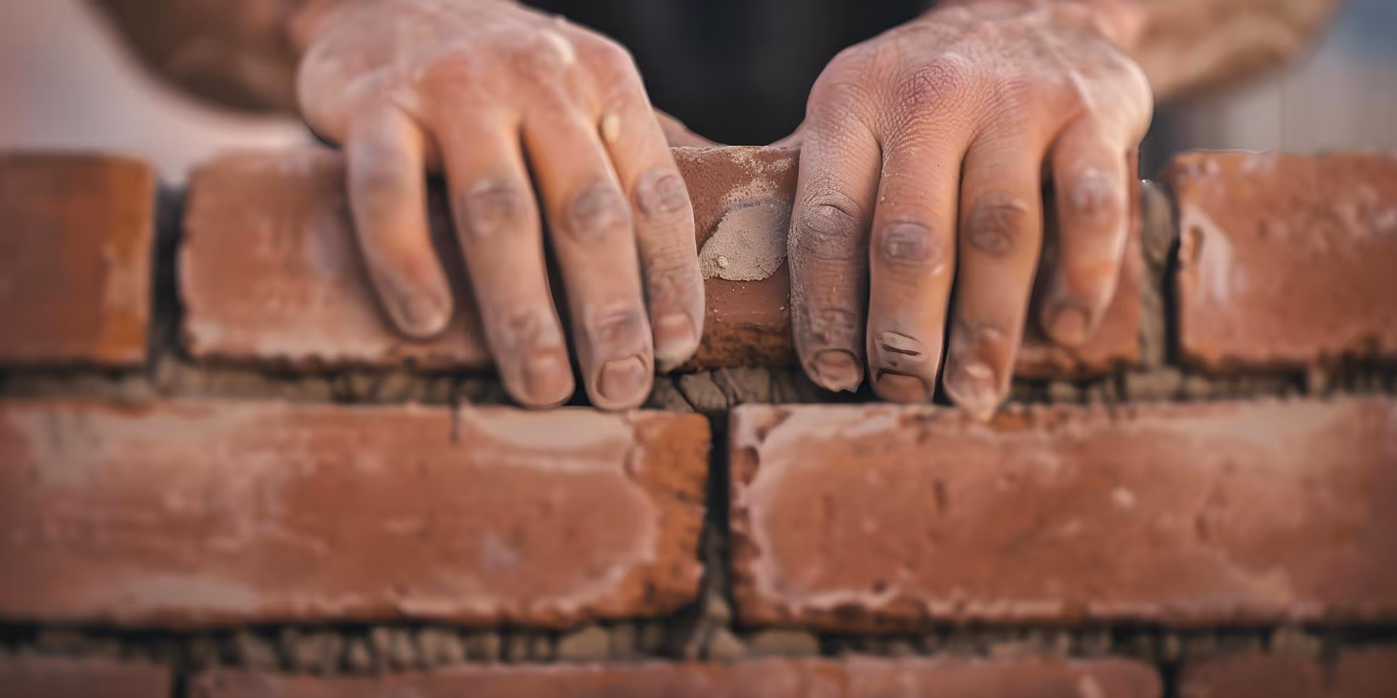 Maçon posant une assise de blocs au cordeau et au niveau sur un chantier de maçonnerie à Clermont-Ferrand